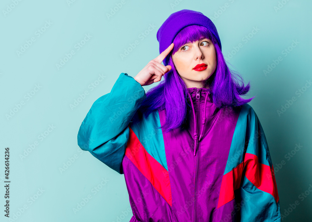 Surprised white girl with purple hair and 80s tracksuit point finger on her head on blue background Surprised white girl with purple hair and 80s tracksuit point finger on her head on blue background