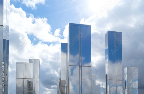 Modern art object in the form of tall buildings against the background of a blue sky with clouds