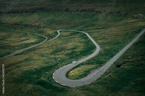 Fotografie White campervan on a scenic winding pass road in grassland on Faroe Islands