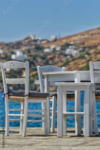 Traditional wooden chairs and table in front of the famous mylopotas beach in Ios cyclades Greece photo