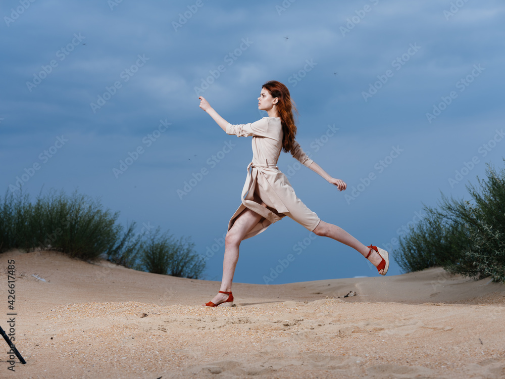 A woman in a beige dress walks with a long stride on the beach A woman in a beige dress walks with a long stride on the beach