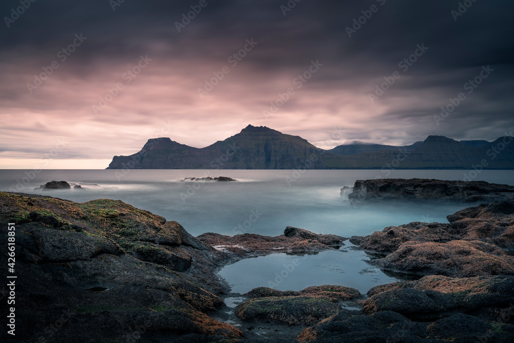 Seaside water pools at Gjogv in sunset with a view of island Kalsoy and ocean, Faroe Islands.