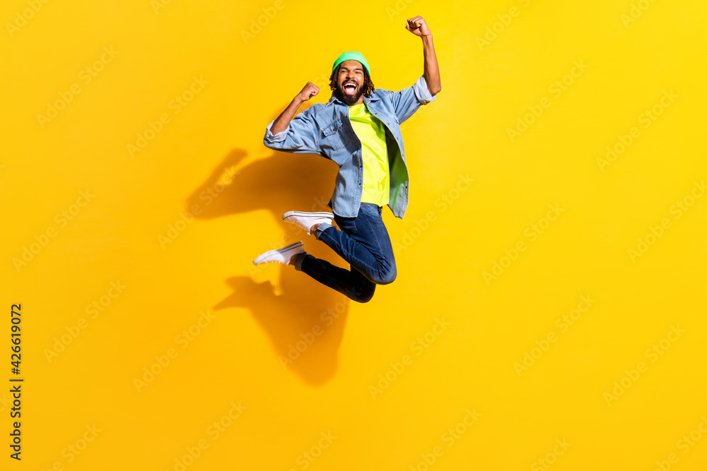 Full size photo of young handsome excited smiling man jumping in victory isolated on yellow color background