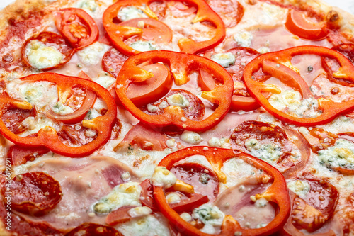 traditional Italian pizza with ham, bell pepper, mozzarella cheese, and tomato sauce. Delicious Mediterranean meal. vertical image, Food recipe background. Close up