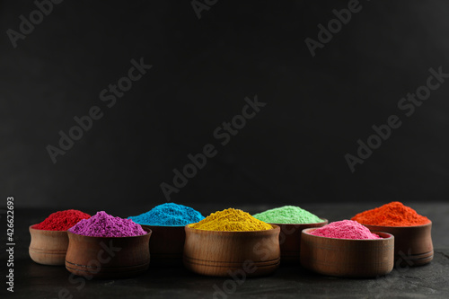 Colorful powder dyes on black background, space for text. Holi festival photo