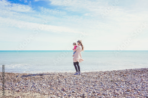 Happy family moment of a young mom enjoying a day on the beach with her baby
