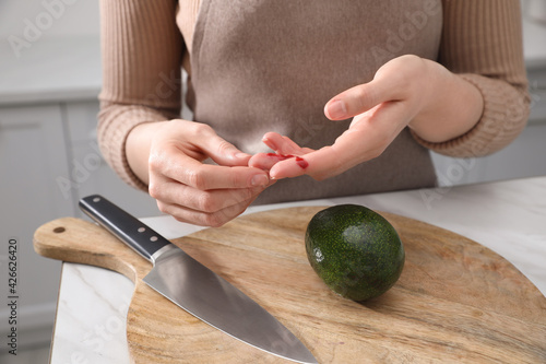 Woman cut finger while cooking in kitchen, closeup