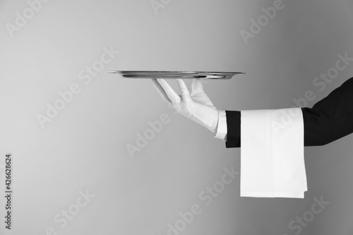 Butler with tray on light grey background, closeup. Space for text photo