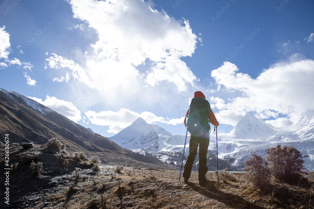 Successful woman backpacker hiking in winter high altitude mountains