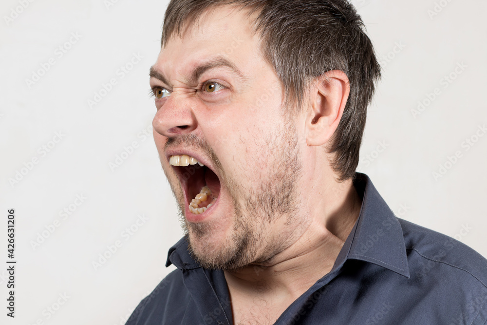 An angry aggressive man screams with mouth open. A human cry at a child or a quarrel in the family. Anger and negative emotion with scream. An angry aggressive man screams with mouth open. A human cry at a child or a quarrel in the family. Anger and negative emotion with scream.