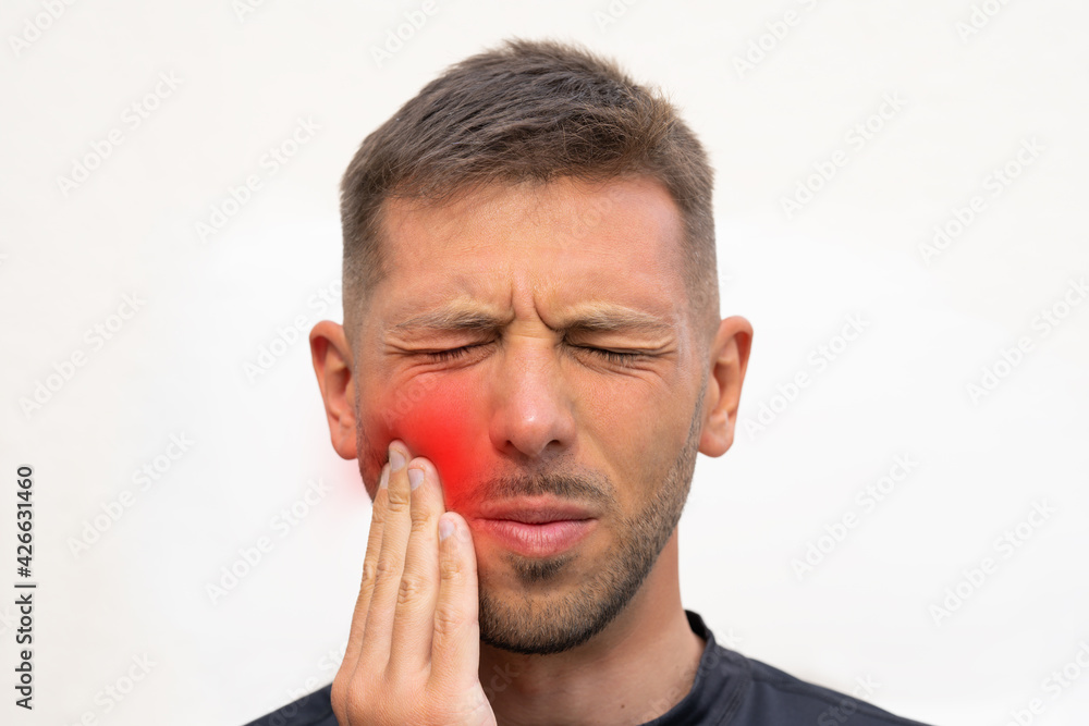 Man touching his cheek because of strong tooth pain. Man suffering from toothache, dental illness or oral diseases. Teeth problem.Man feeling tooth pain Man touching his cheek because of strong tooth pain. Man suffering from toothache, dental illness or oral diseases. Teeth problem.Man feeling tooth pain