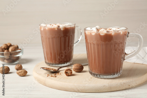 Cocoa drink with nutmegs and marshmallows on white wooden table