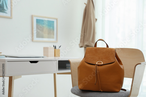 Stylish urban backpack on chair in room