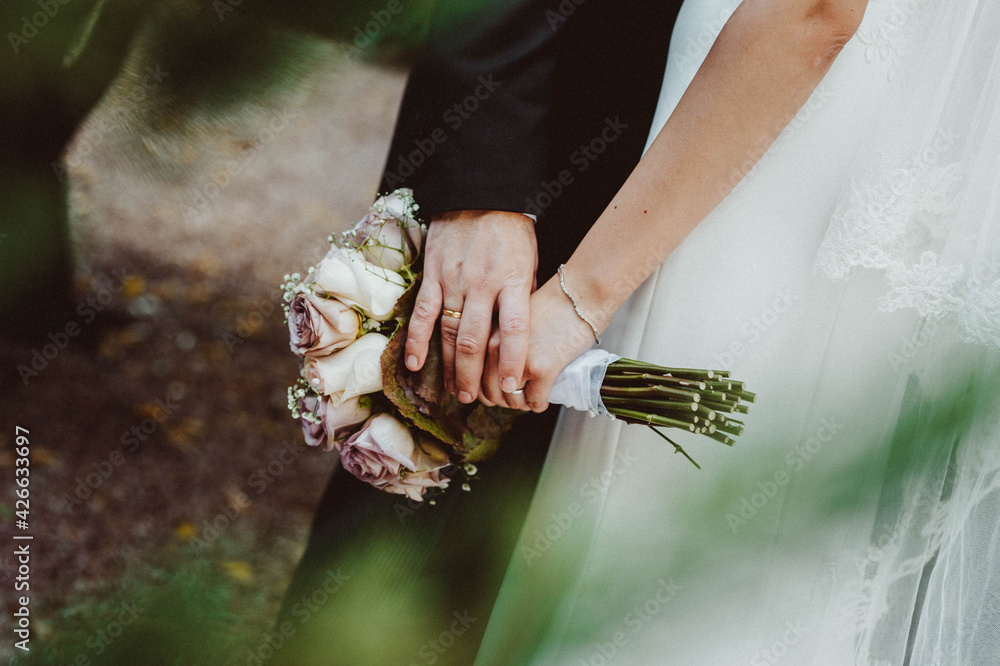 Novios sujetando el ramo con las manos. Recién casados. Ramo de novia. Ramo de flores.