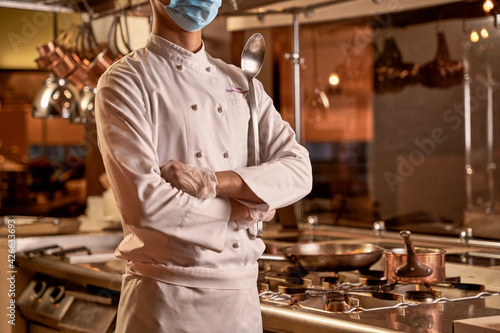 Proud chef standing with crossed arms in kitchen