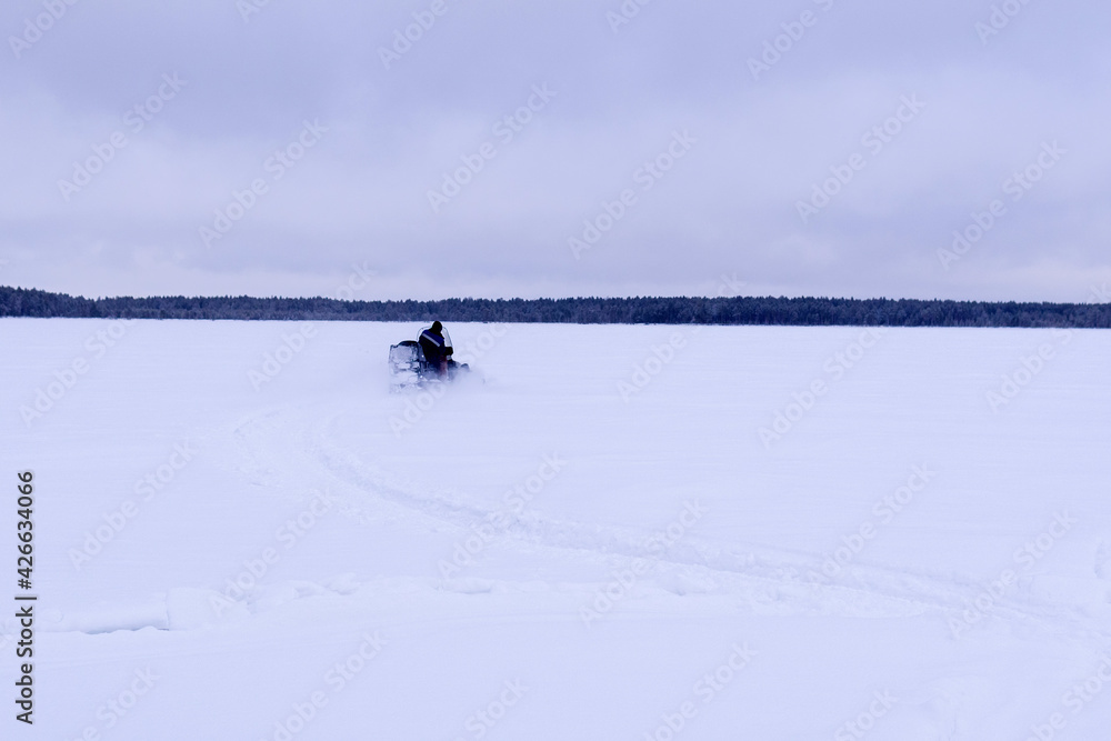 snowmobile fisherman is riding along the winter lake. landscape winter snowmobile fisherman is riding along the winter lake. landscape winter