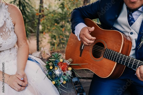 Hombre tocando la guitarra para su esposa. Novios recién casados. Momento musical en boda.