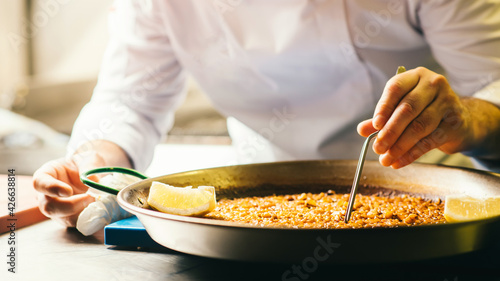 Cooking paella chef checks readiness with tweezers - Spanish food