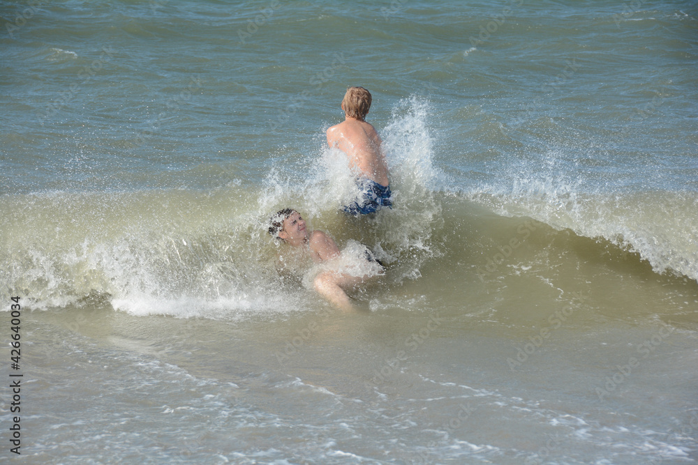 Two children in the middle of a breaking wave