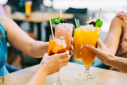 Group of young friends clinking glasses with cocktails in hand celebrating in the afternoon on the terrace