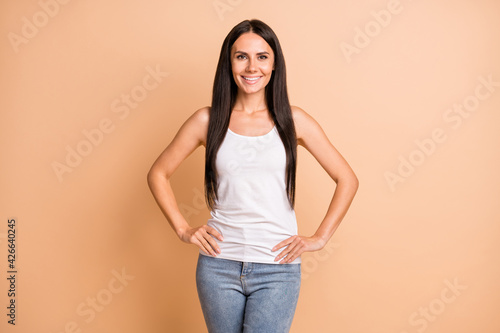 Photo of optimistic brunette girl wear white top jeans isolated on pastel beige color background