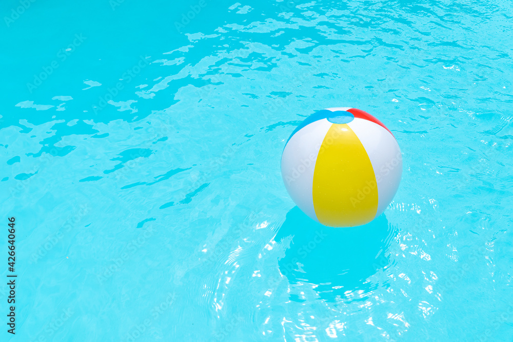 Beach Ball Floating on water surface of a swimming pool. Summer background. Copy space