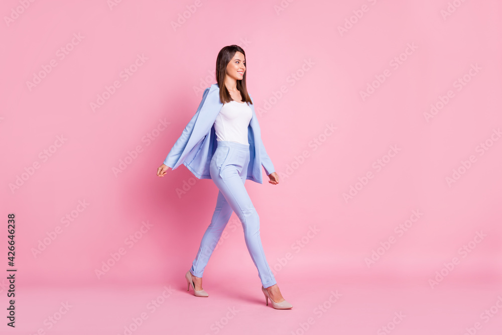 Profile side full size photo of young attractive smiling positive confident bossy woman go walk isolated on pink color background Profile side full size photo of young attractive smiling positive confident bossy woman go walk isolated on pink color background