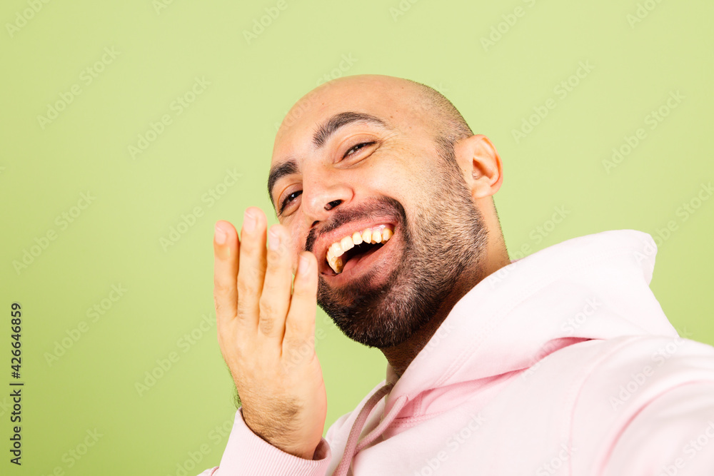 Young bald caucasian man in pink hoodie isolated on green background positive cheerful take photo selfie Young bald caucasian man in pink hoodie isolated on green background positive cheerful take photo selfie