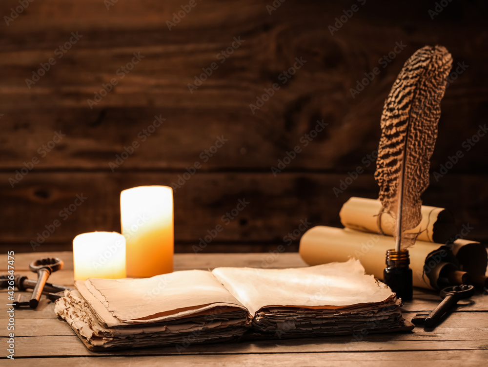Old book with scrolls, feather, keys and candles on wooden background - obrazy, fototapety, plakaty 