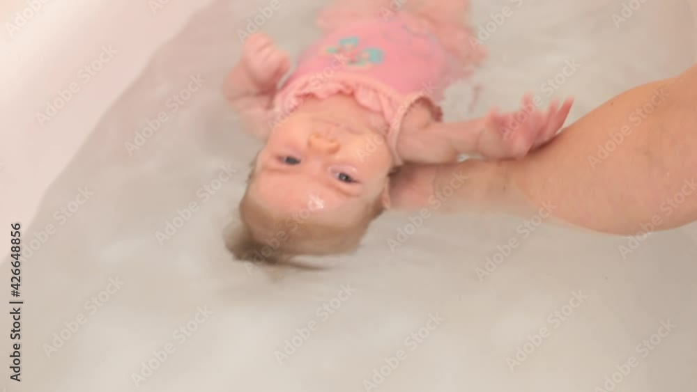Learning to dive a baby in a newborn's bathtub, a reflex is expressed that prevents water from entering the respiratory tract. Toddler swimming workout. Learning to dive a baby in a newborn's bathtub, a reflex is expressed that prevents water from entering the respiratory tract. Toddler swimming workout.