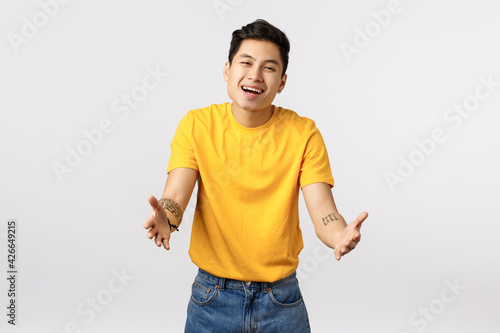 Tender and cute charming asian young boyfriend with yellow t-shirt, return home want hug his lovely dog, stretch hands forward to cuddle, embrace loved person, smiling with amiration and joy photo