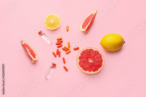 Fototapeta Naklejka Na Ścianę i Meble -  Bottles with vitamin C, pills and citrus fruits on color background