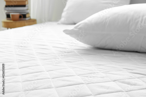 Soft orthopedic mattress on bed in room, closeup photo