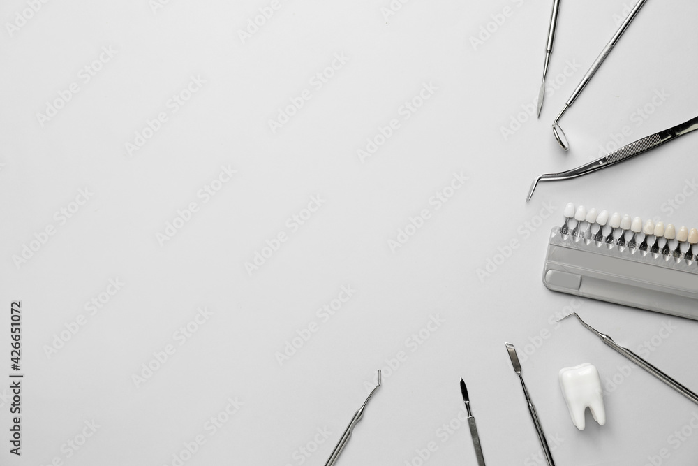 Naklejka premium Dentist's tools and teeth color samples on light background