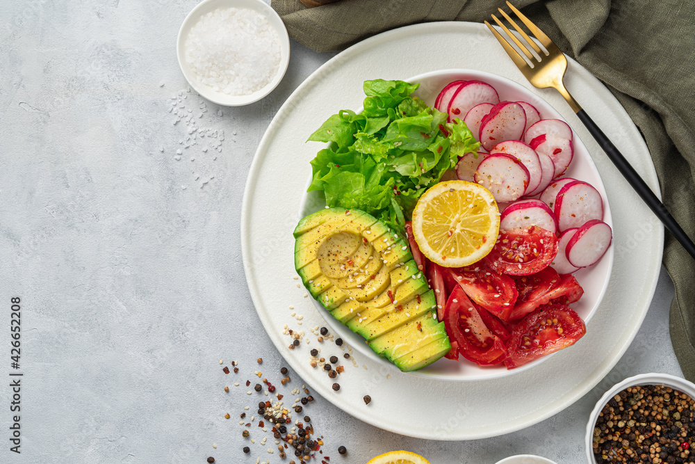 Fresh, summer salad with avocado, tomato and radish on a gray table. Top view, copy space. Fresh, summer salad with avocado, tomato and radish on a gray table. Top view, copy space.