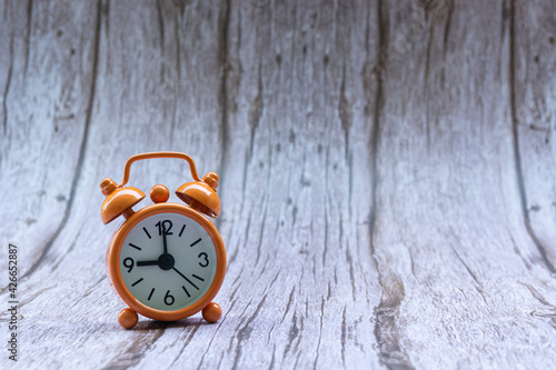 Orange old retro style alarm clock on wooden background photo