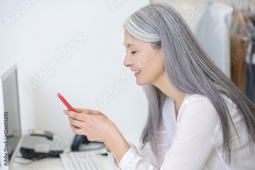 Profile of woman behind counter looking at smartphone