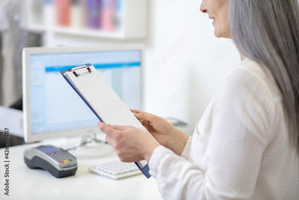 Woman reading document standing behind counter Woman reading document standing behind counter