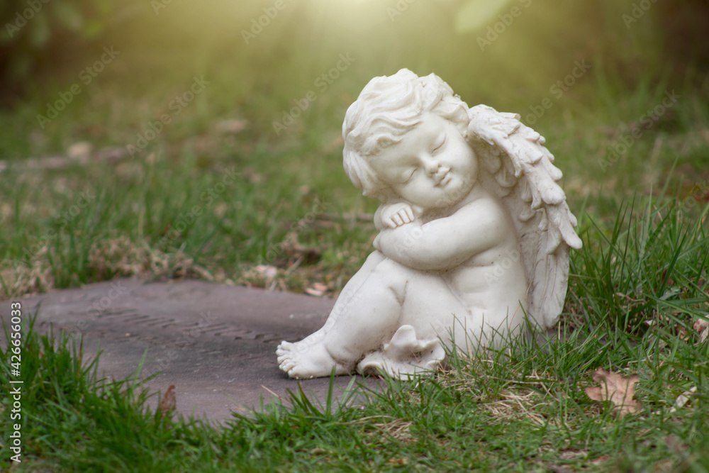 Closeup of dreaming putto or child angel figurine on a grave Closeup of dreaming putto or child angel figurine on a grave