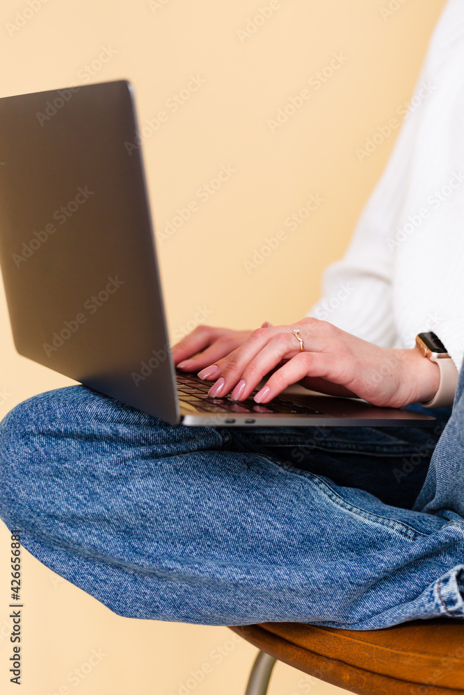 Pretty european woman in casual white sweater isolated on peach background sit on chair with laptop computer on knees businesswoman student freelance Pretty european woman in casual white sweater isolated on peach background sit on chair with laptop computer on knees businesswoman student freelance