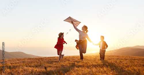 Happy family mother and kids launch kite on nature at sunset © JenkoAtaman