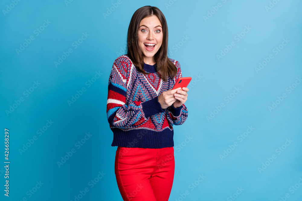 Photo of young attractive girl happy positive smile chat type sms smartphone read browse isolated over blue color background Photo of young attractive girl happy positive smile chat type sms smartphone read browse isolated over blue color background