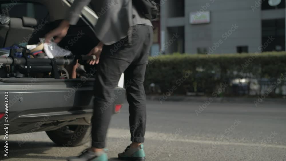 Energy efficient travel vehicle concept of 4k Resolution. An Asian man is keeping a scooter in his car. Energy efficient travel vehicle concept of 4k Resolution. An Asian man is keeping a scooter in his car.
