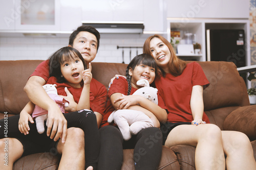 Young family watching TV together at home and having fun together