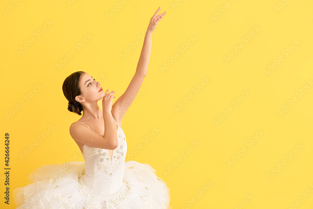 Naklejka premium Beautiful young ballerina on color background