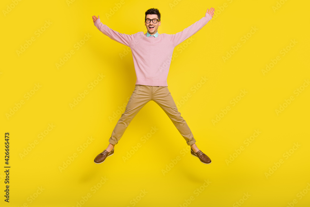 Full size photo of young happy positive excited crazy smiling man jumping in star pose isolated on yellow color background