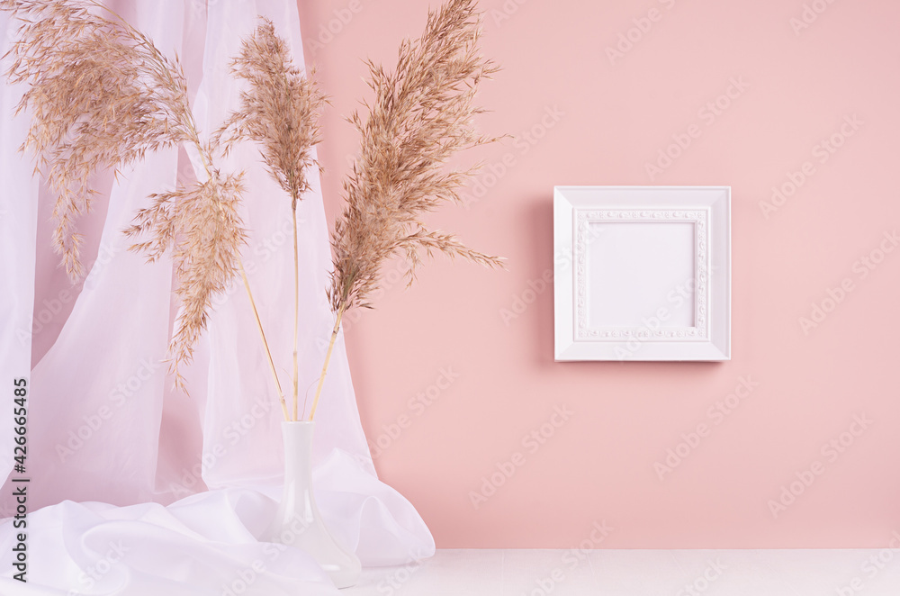 Calm home decor with square blank photo frame for text hanging on pink wall, silk curtain, fluffy reeds bouquet on white wood table. Template for display and portfolio.
