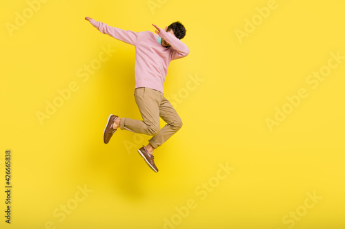 Full size photo of young funky funny man jumping showing dab cover close face isolated on yellow color background