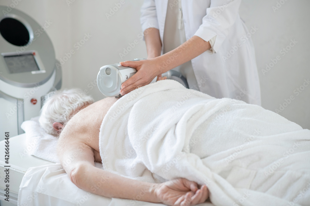 Fototapeta premium Physiotherapist doing anti-ostechondrosis procedures to a female patient