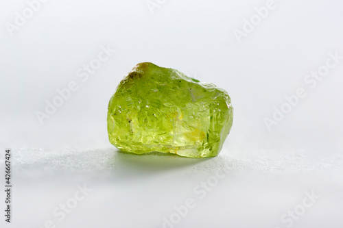 Natural chrysolite, peridot, olivine apple green color transparent raw rough crystal. Earth mined untreated, unheated, ready for faceting or cabochon making. Close-up on white background. photo